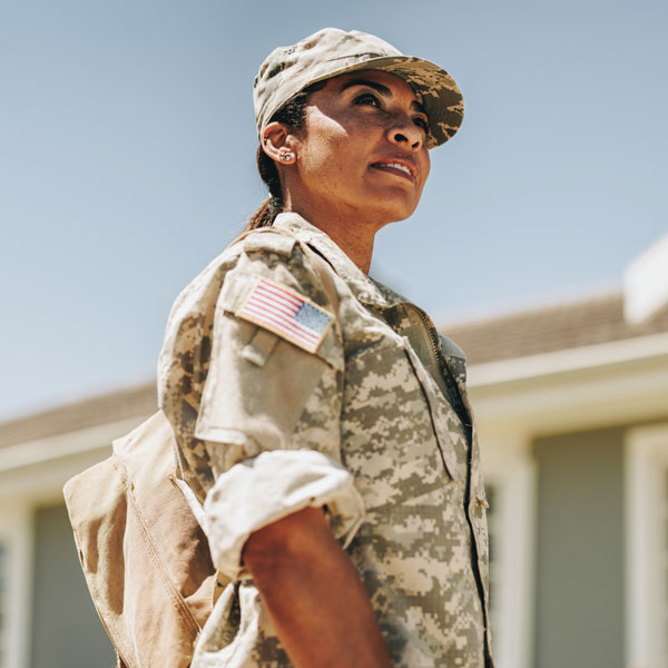 Military woman in uniform standing in front of a home
